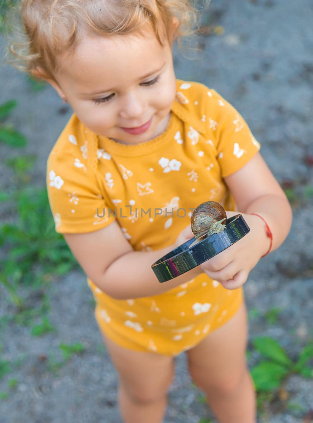The child looks at the snail. Selective focus. Animal.