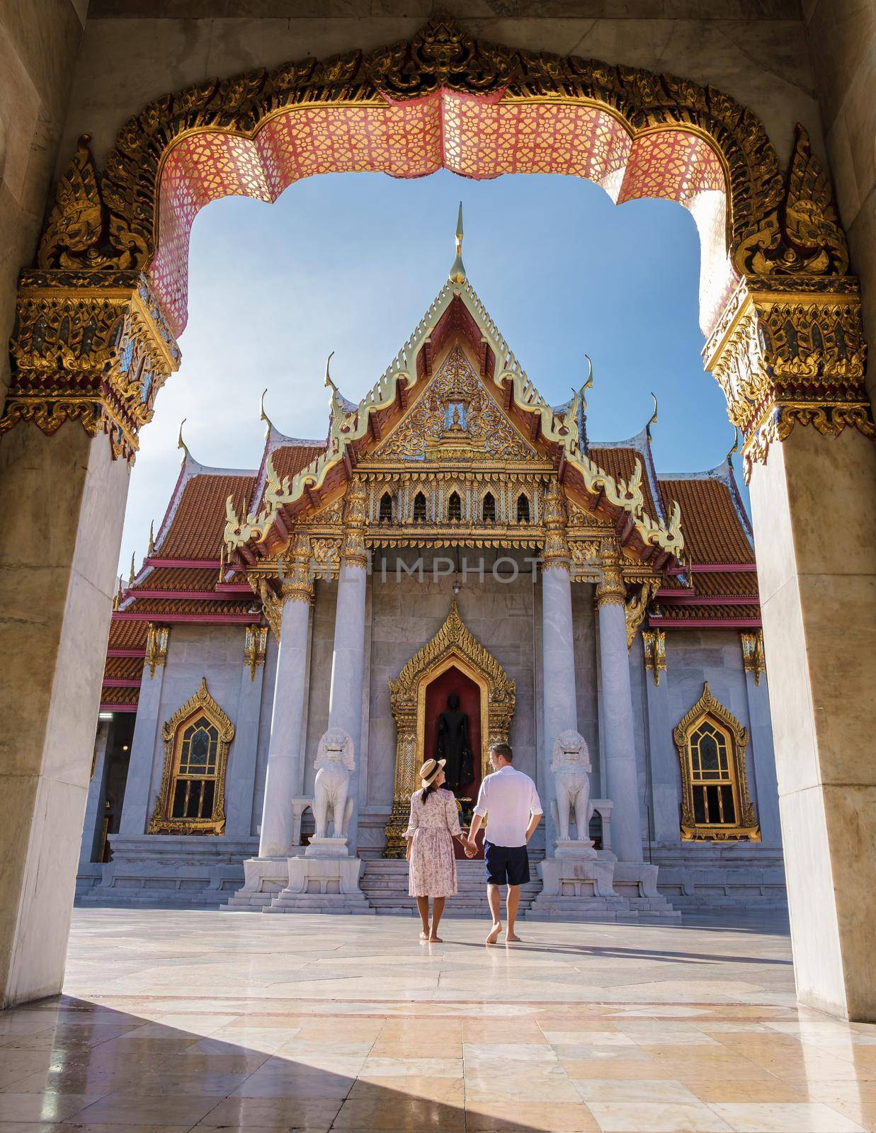 Wat Benchamabophit temple in Bangkok Thailand, The Marble temple in Bangkok. Asian woman with hat and European men visiting a temple, a couple on a city trip in Bangkok