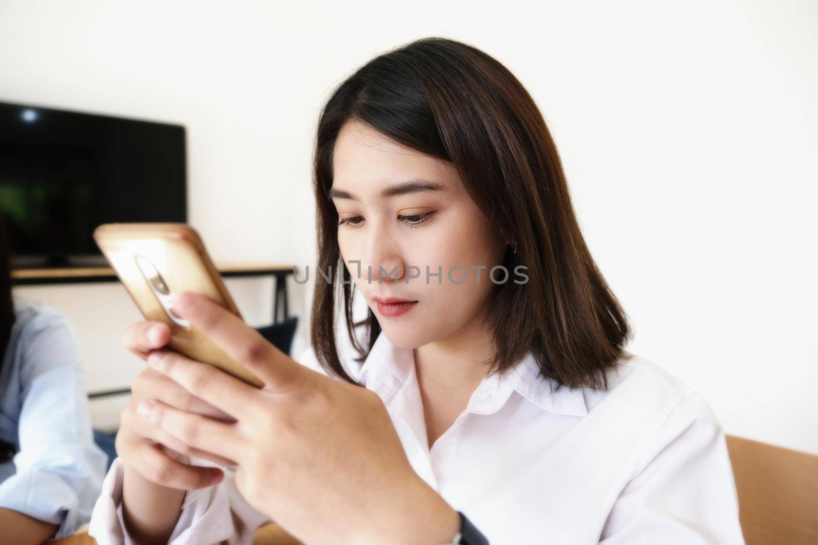 woman using mobile phone to social media in office. by Manastrong