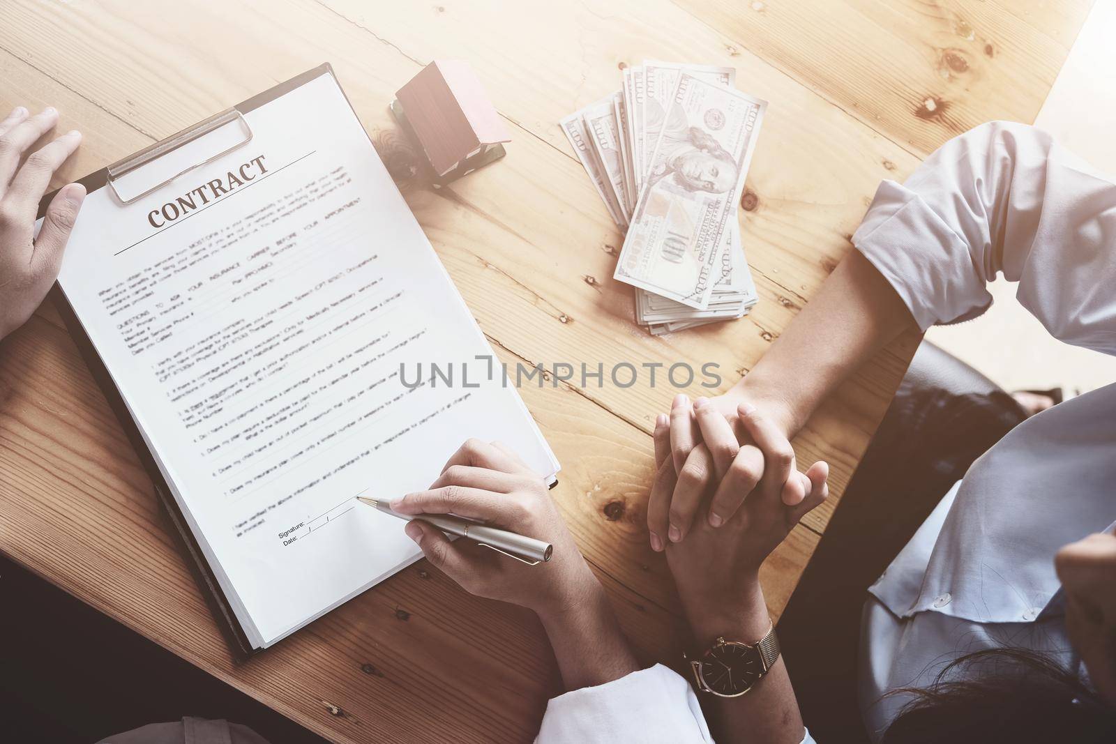 The customer holds a pen and reads the conditions in order to sign a house purchase contract with home insurance documents with the salesperson