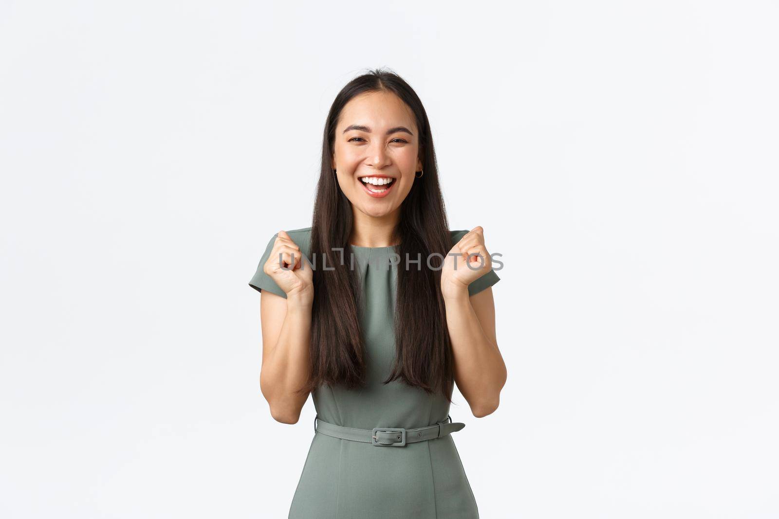 Small business owners, women entrepreneurs concept. Excited happy asian woman in dress, businesswoman winning or achieve goal, fist pump as celebrating victory, triumphing over white background.