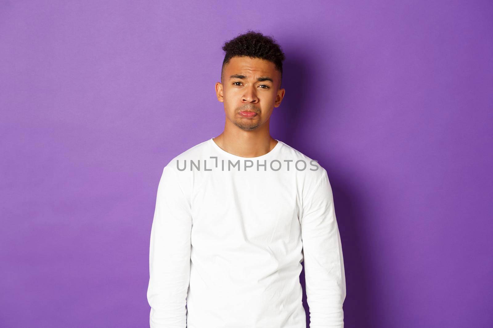 Portrait if silly african-american guy whining, begging for something, crying and looking sad at camera, standing over purple background by Benzoix