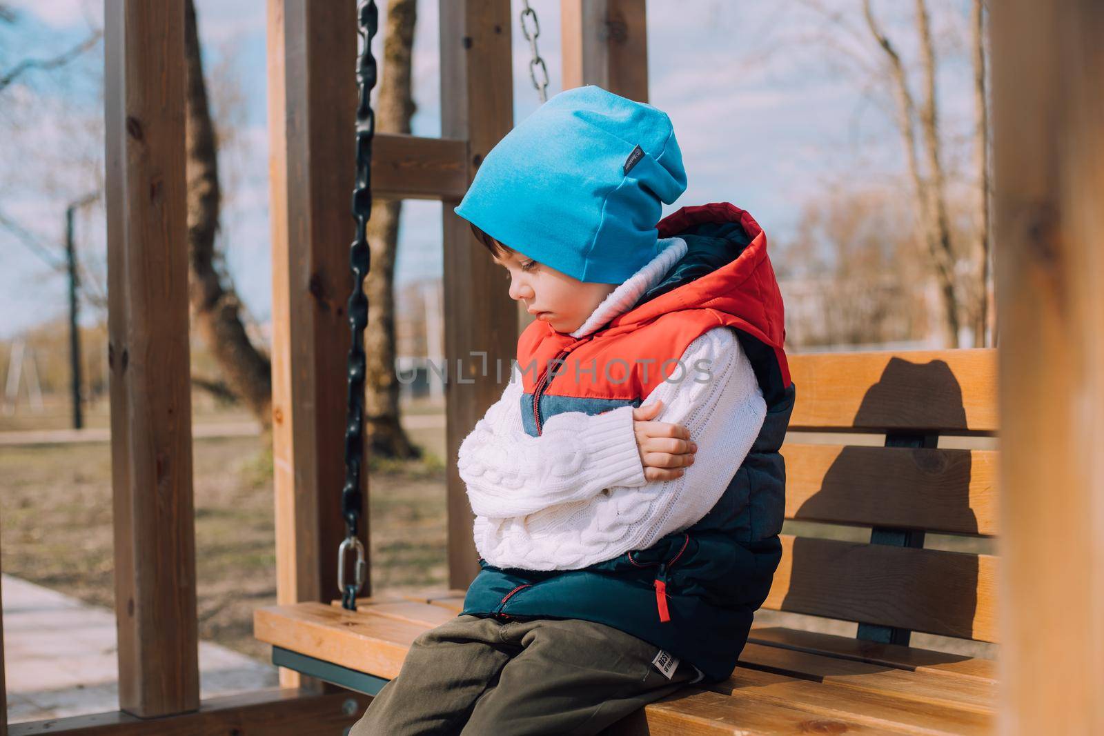 The offended boy is sitting on a lifestyle bench . Childish grievances. Childish anger. An article about children's emotions. An article about the psychology of children. Transitional age