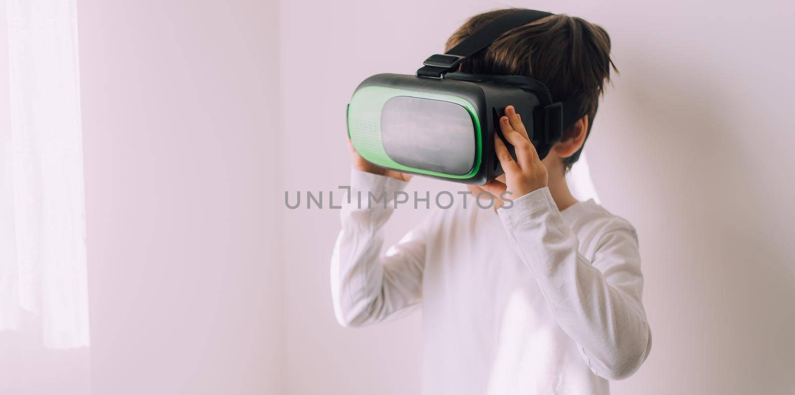 A boy is playing vr glasses on a white copyspace wall . An article about modern gadgets. An article about modern technologies. Place under the text