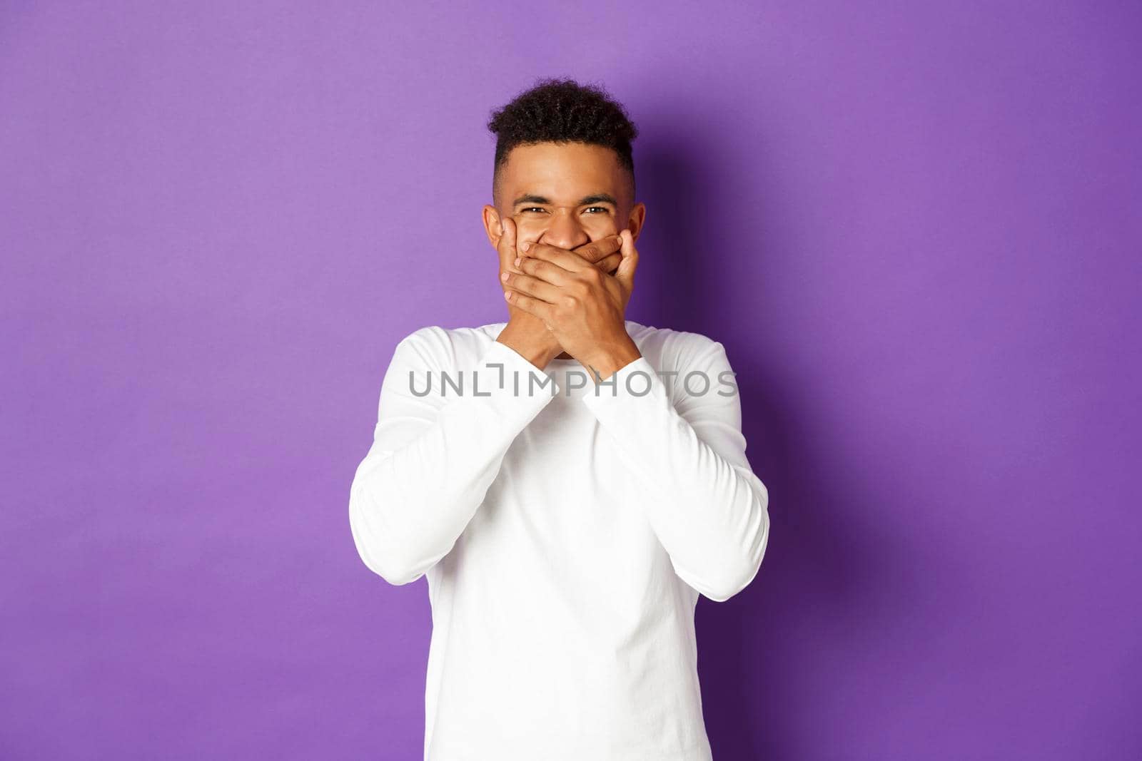 Image of shocked and disgusted african-american man, cover mouth, refrain from vomiting, standing over purple background.