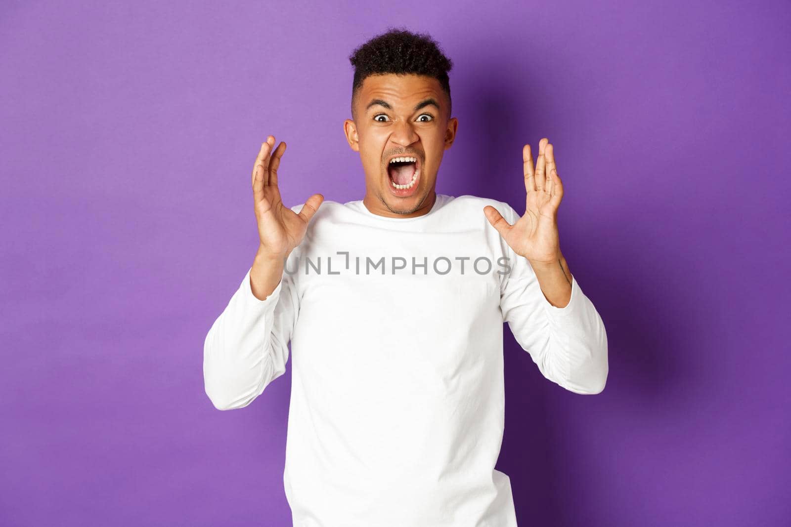 Image of frustrated african-american man, shouting and looking angry, losing temper from anger, standing distressed against purple background.
