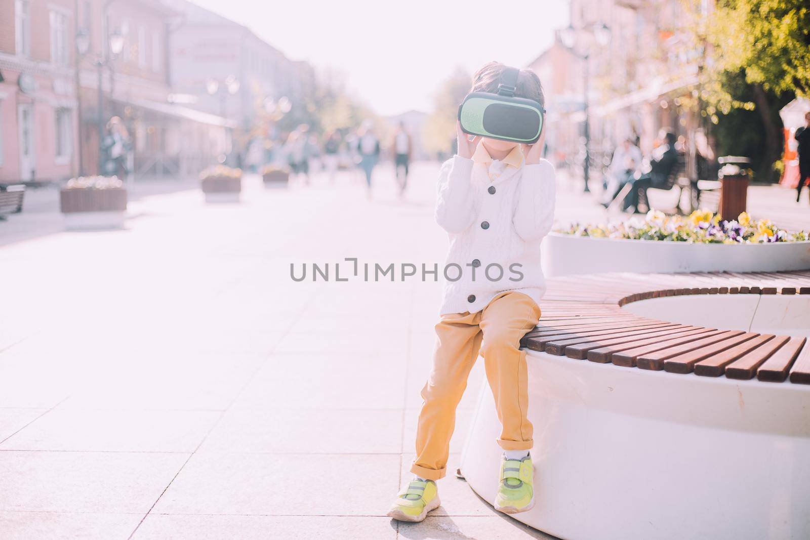 A boy is playing virtual reality glasses on the street . Modern gadgets. Children's games. The choice of virtual glasses. An article about virtual glasses. Modern children. Copy Space