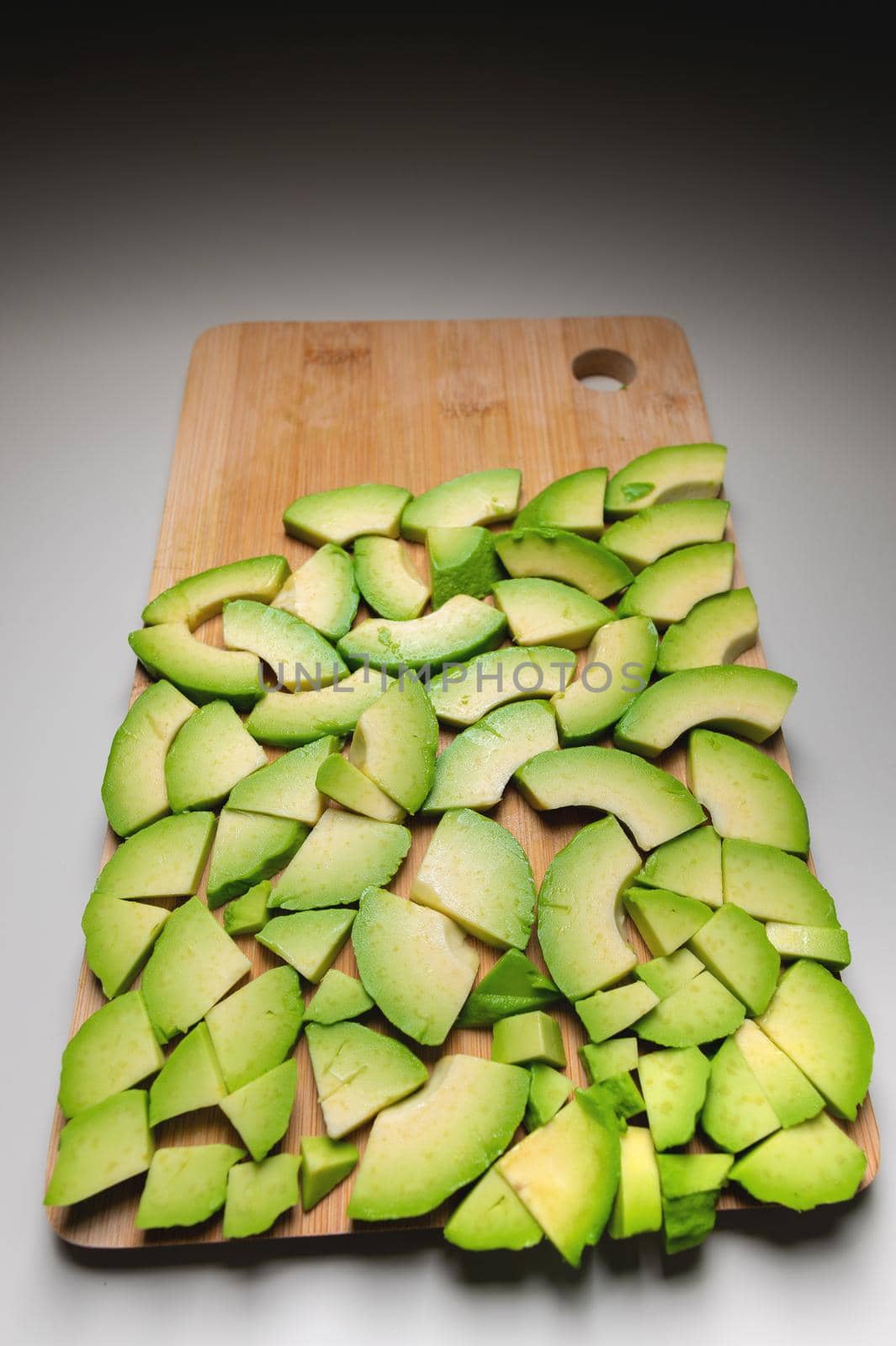 sliced avocado into small pieces lie on a cutting wooden board. copy space.
