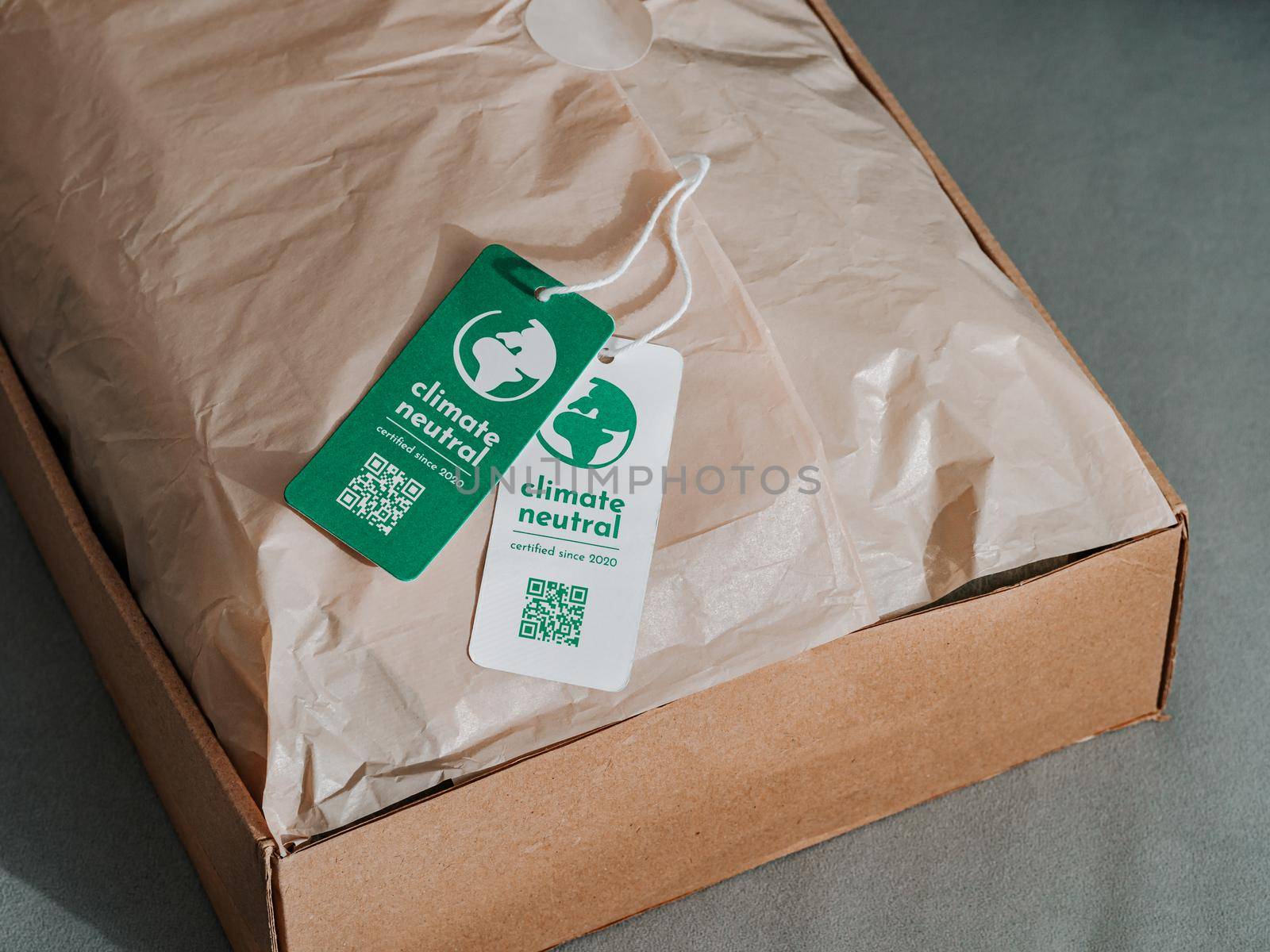 Carbon neutral product in craft corrugated box with label Climate neutral. Carbon neutral label concept in apparel, fashion, logistics indusrty and ethical consumption. Increasing awareness for customers about carbon footpint
