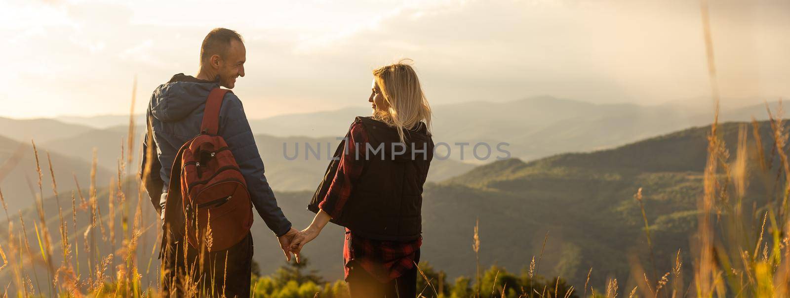 Happy traveler young couple resting in the mountains at sunset in spring or summer season. by Andelov13