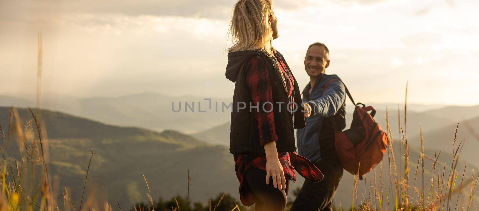 travel to mountains, tourists hikers with backpacks at sunset enjoying panoramic view.