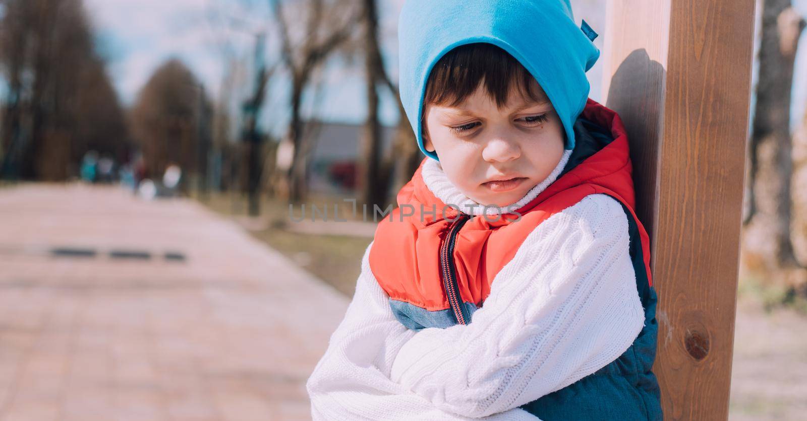 The offended boy is sitting on a lifestyle bench . Childish grievances. Childish anger. An article about children's emotions. An article about the psychology of children. Transitional age