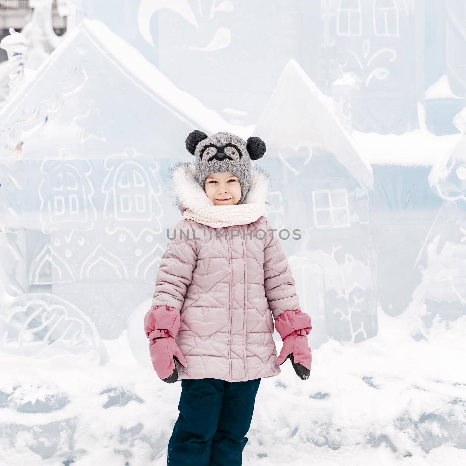 caucasian child girl posing near the ice palace on a winter day