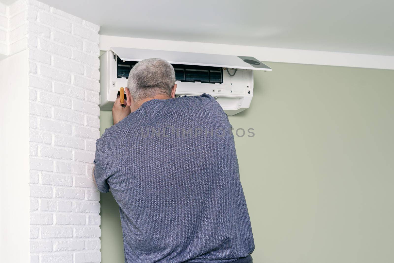 man using screwdriver to repairing air conditioner by Lena_Ogurtsova