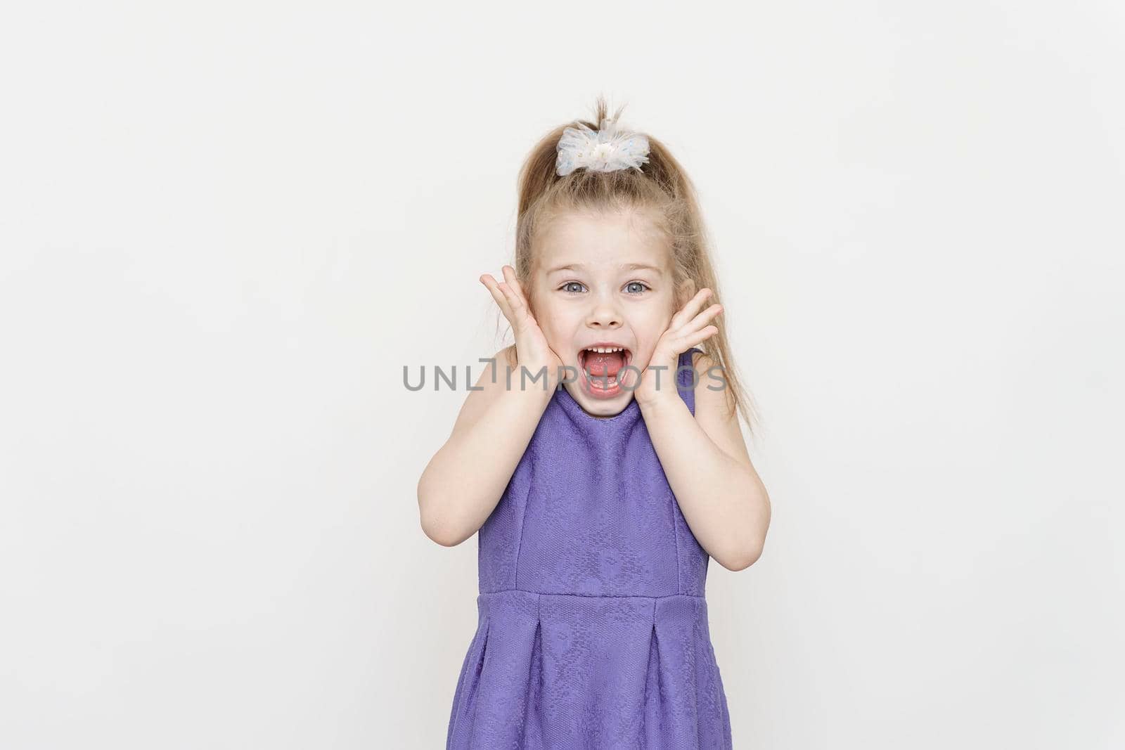 portrait of a cute 5 year old girl with a shocked expression on a light background