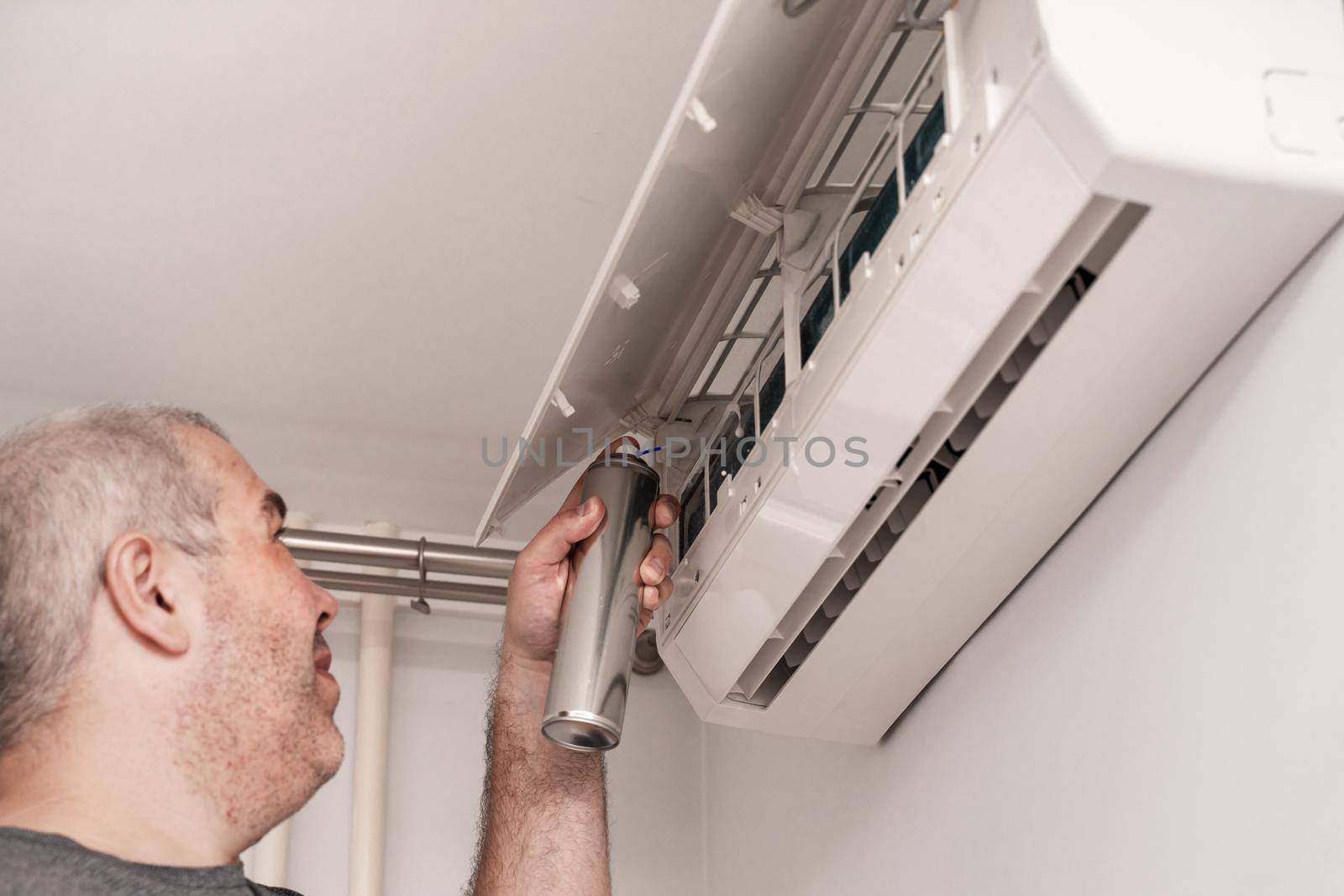 man cleaning home air conditioner with antibacterial spray by Lena_Ogurtsova