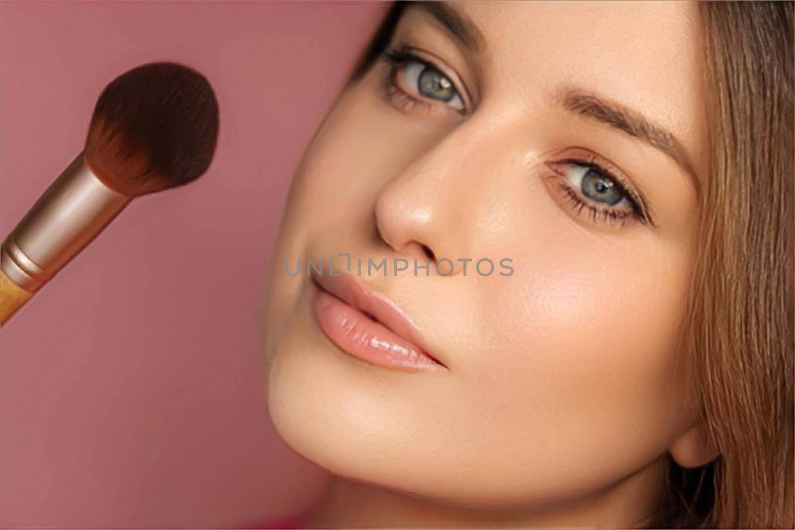 Beautiful young woman applying cosmetic powder product with make-up bamboo brush, beauty, makeup and skincare cosmetics model face portrait on pink background, closeup