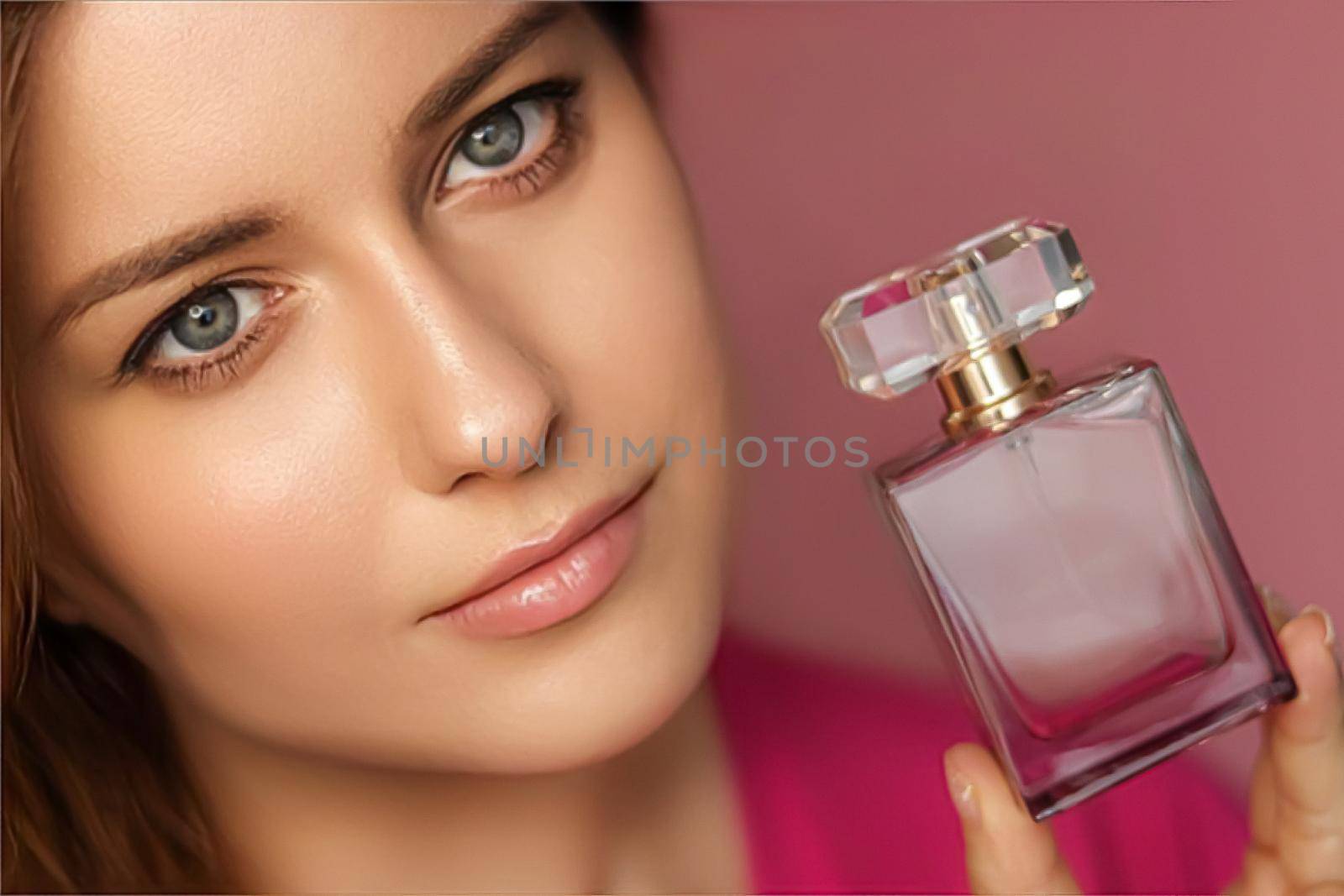 Perfume, beauty product and cosmetics model face portrait on pink background, beautiful woman holding fragrance bottle with floral feminine scent, fashion and makeup concept