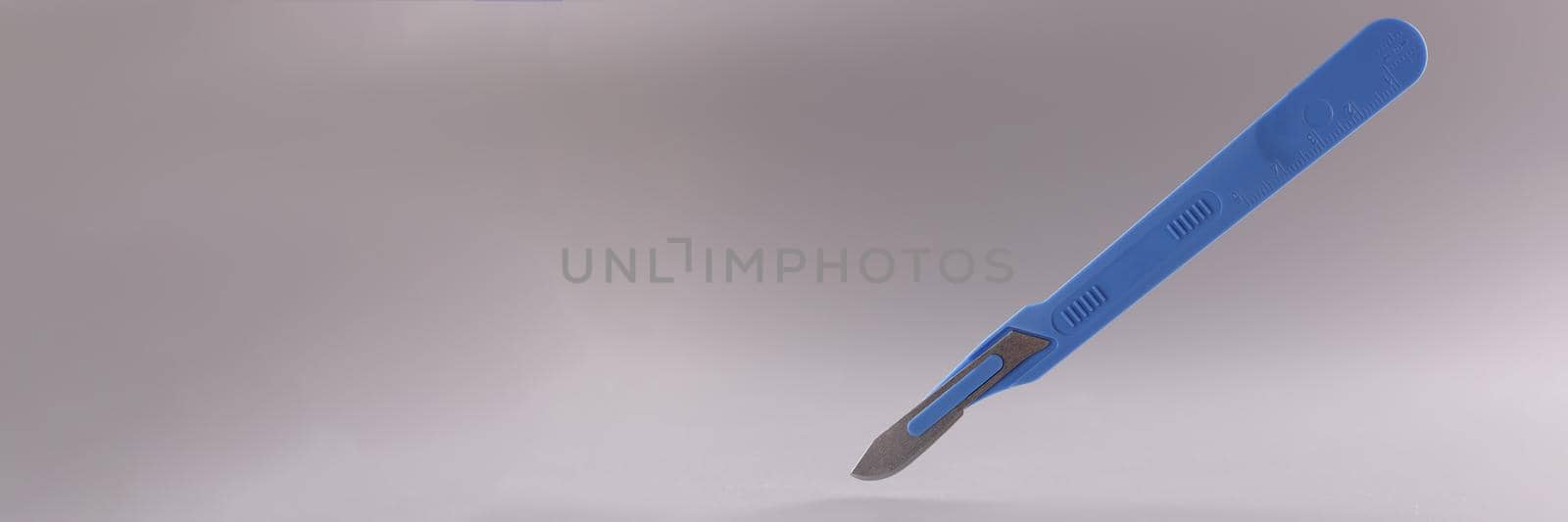 Medical scalpel with blue handle on gray background by kuprevich