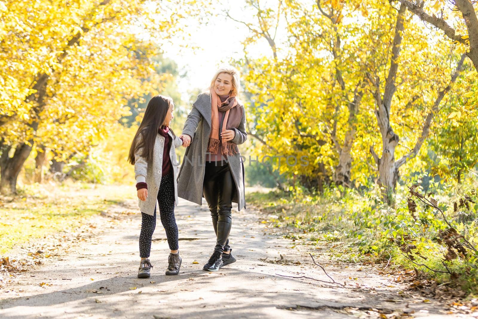 Young mother playing with her daughter in autumn park by Andelov13