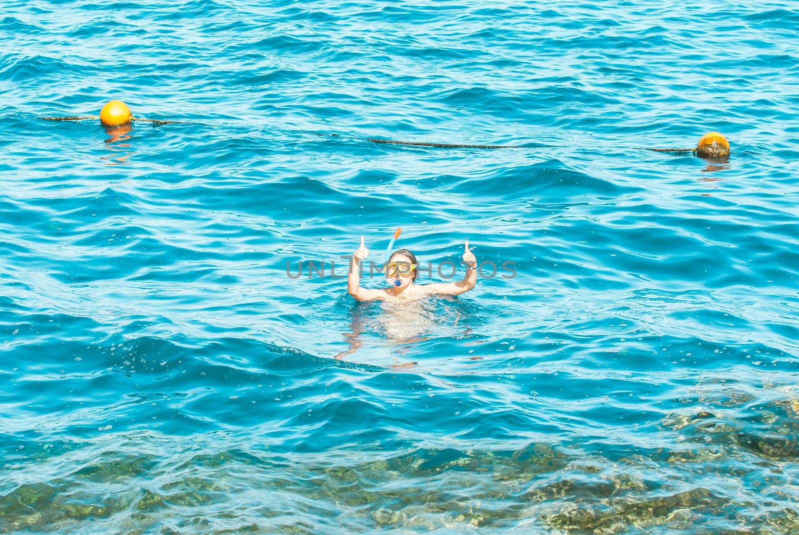 young girl is enjoying diving in the blue sea by maramorosz