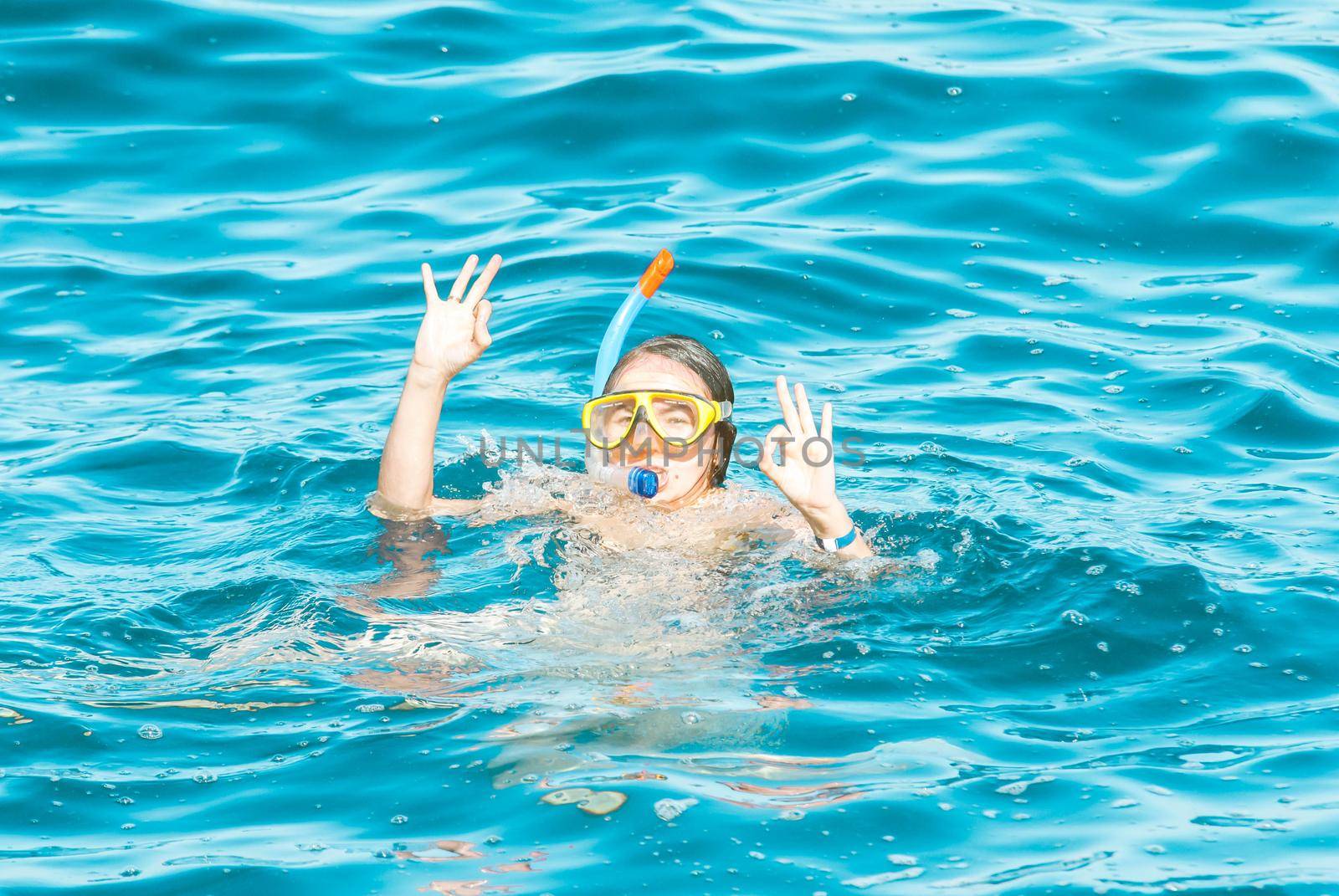 young girl is enjoying diving in the blue sea by maramorosz