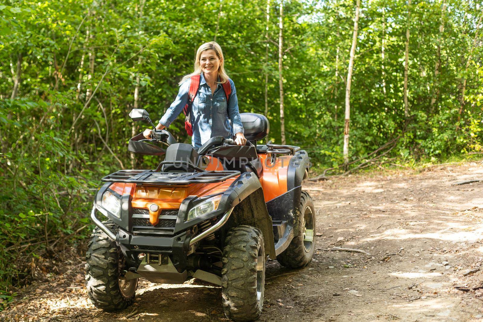 Young woman on quad bike on a trail. Young woman driving all terrain vehicle in nature on a sunny day.