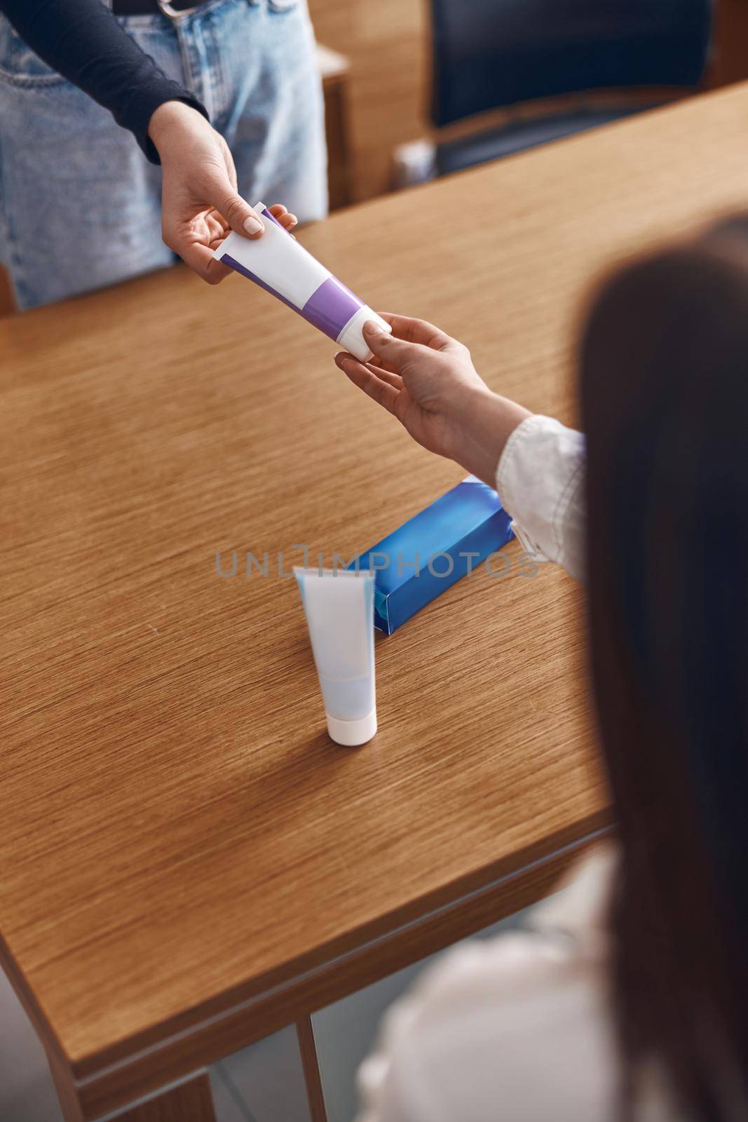 Happy woman is taking a toothpaste from hands of clinic personal