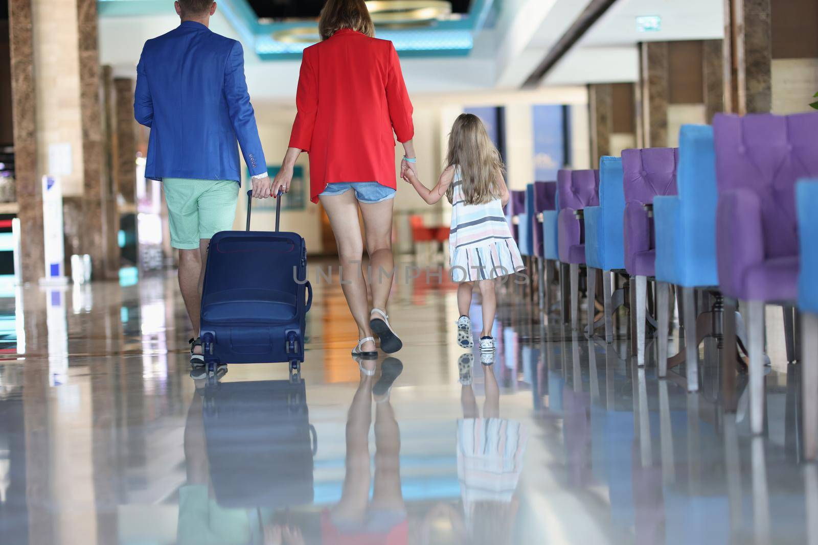 Rear view of family with suitcase while walking in airport or hotel by kuprevich