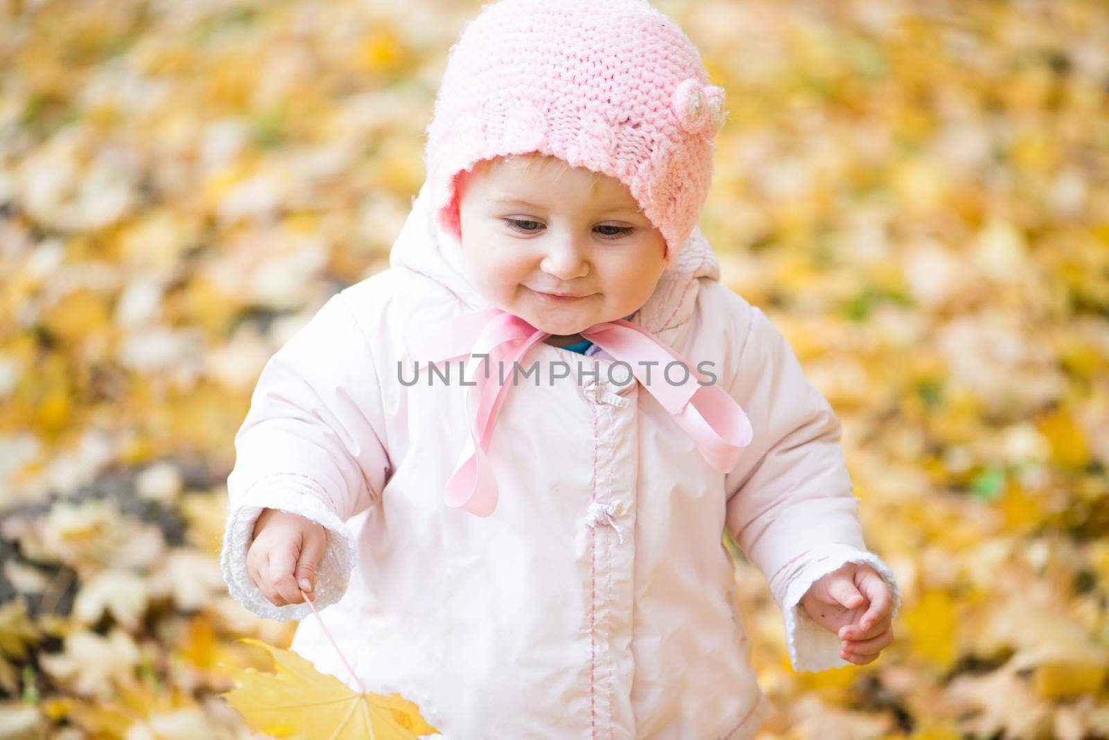 baby girl playing in the park with autumn leaves