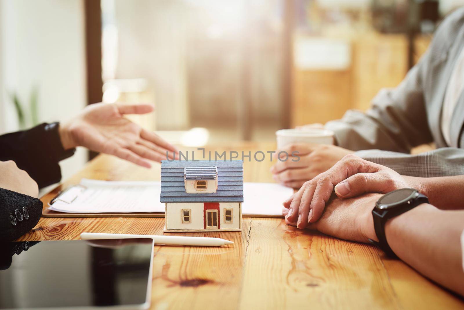 A spouse entering a home contract is reading the terms of the loan interest agreement that the bank officer or real estate agent is offering before signing by Manastrong