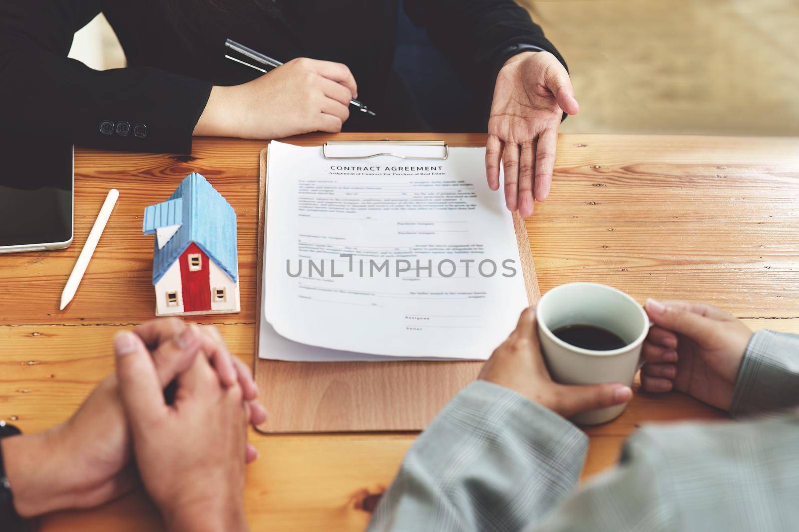 A spouse entering a home contract is reading the terms of the loan interest agreement that the bank officer or real estate agent is offering before signing.