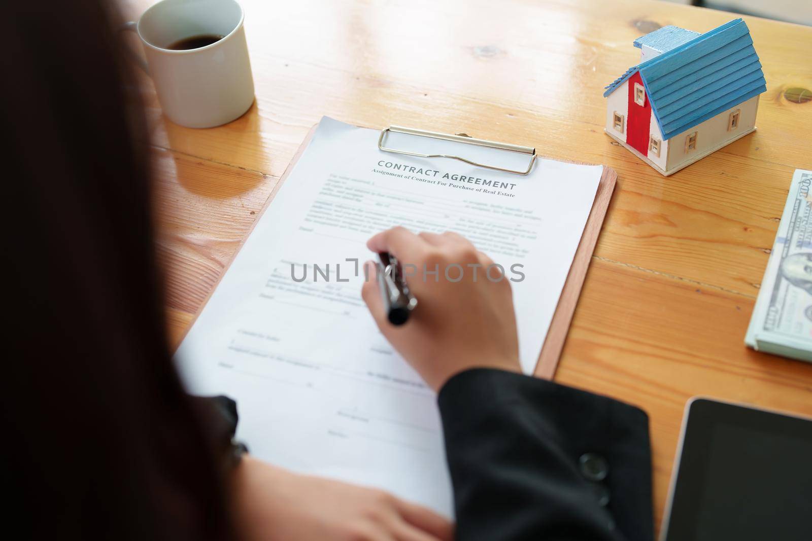 Asian female bank employee asking a customer to read the contract before signing to agree to buy a house, real estate concepts.