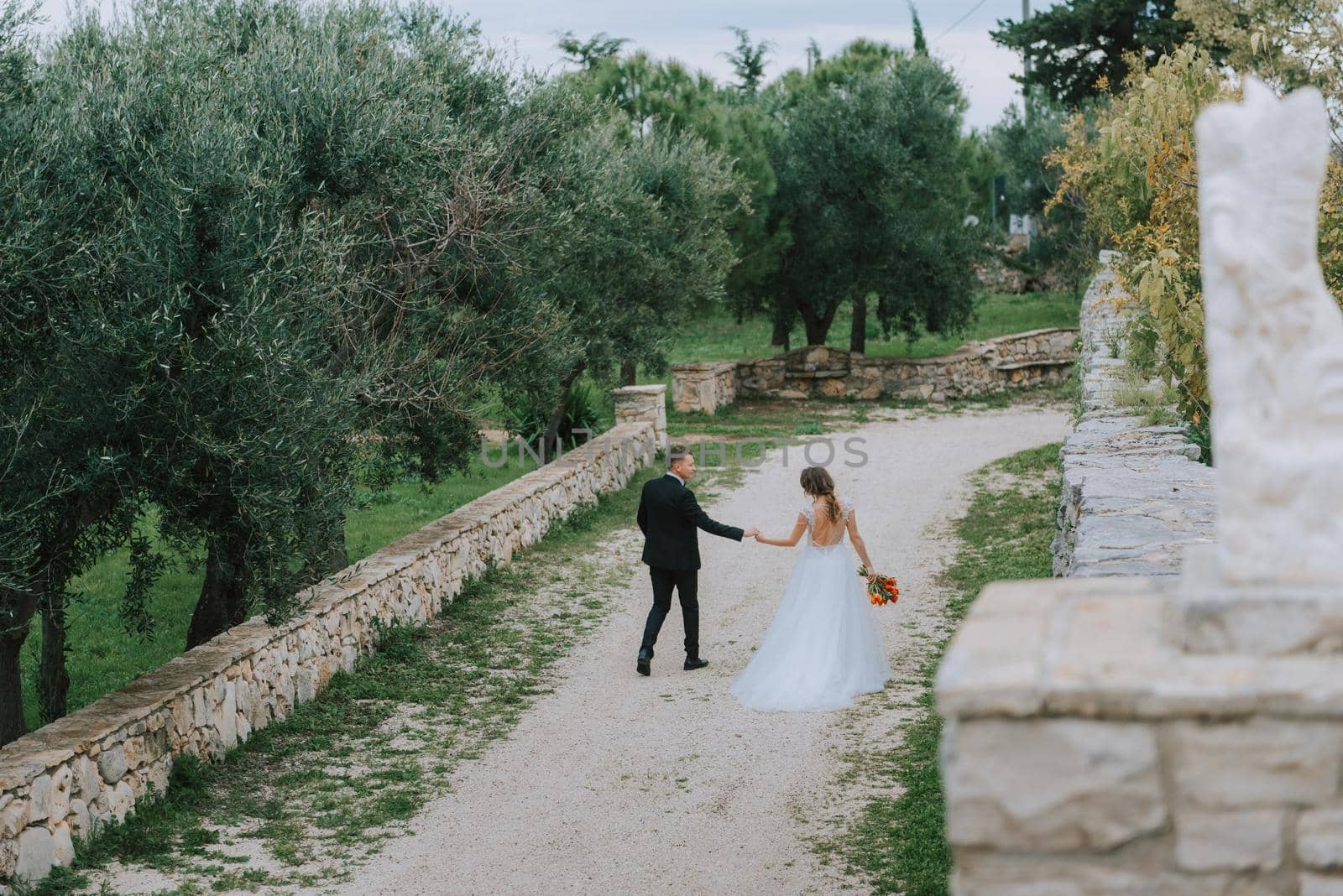 Happy stylish smiling couple walking in Tuscany, Italy on their wedding day. The bride and groom walk down the street by the hands. A stylish young couple walks. Husband and wife communicate nicely. Lovers run through the streets of the city.