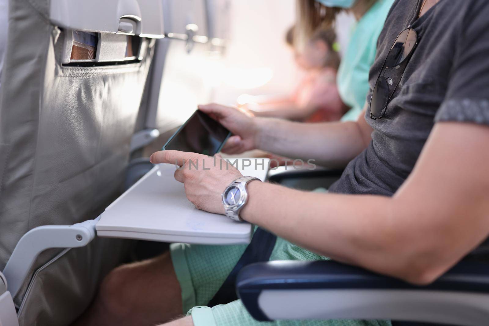 Man hands with a smartphone sits in cabin of airplane or train. Travel app concept