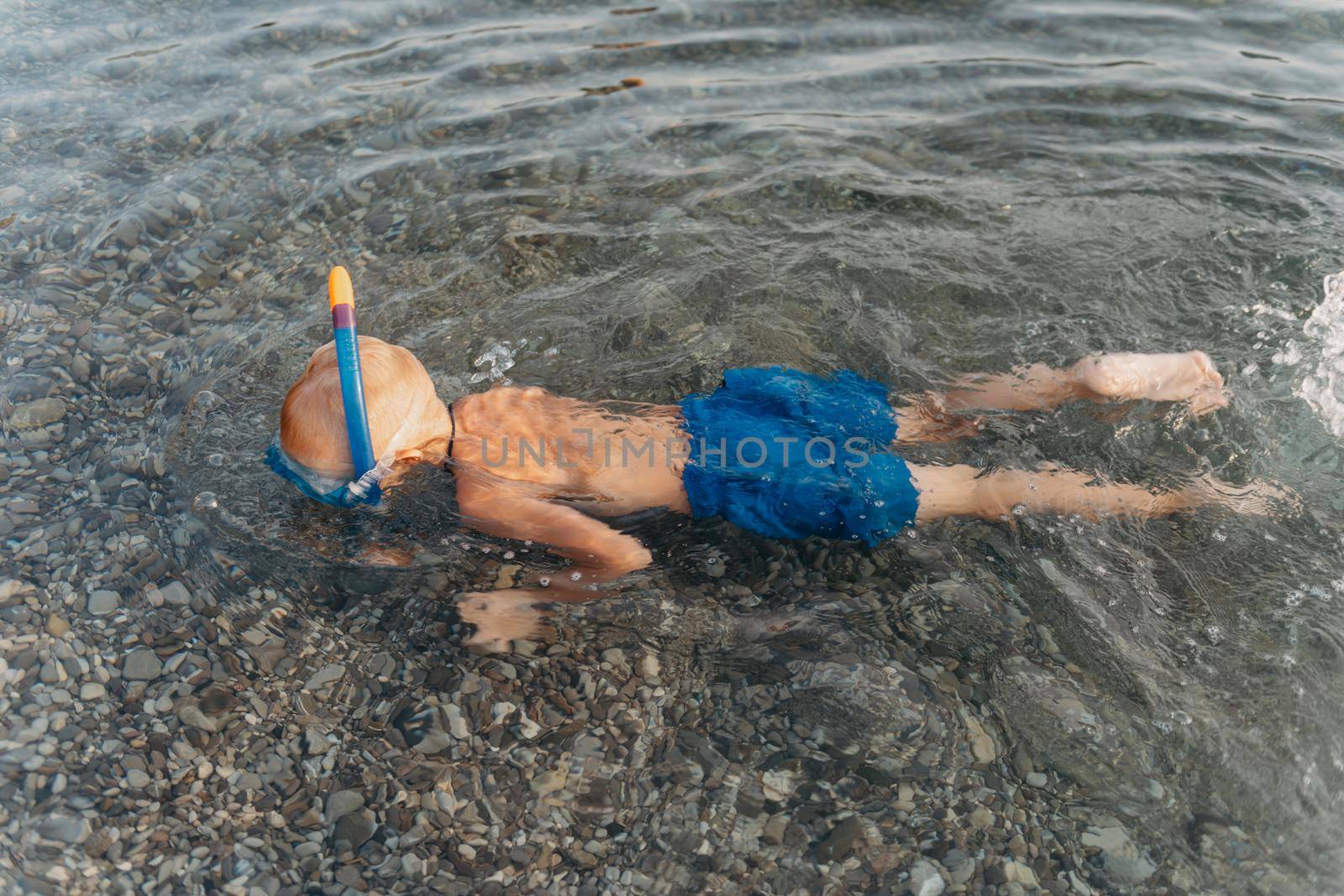 Cute happy little boy swimming and snorking in the sea. Child wearing snorkeling mask diving underwater, little boy enjoy swim underwater on tropical resort by Andrii_Ko