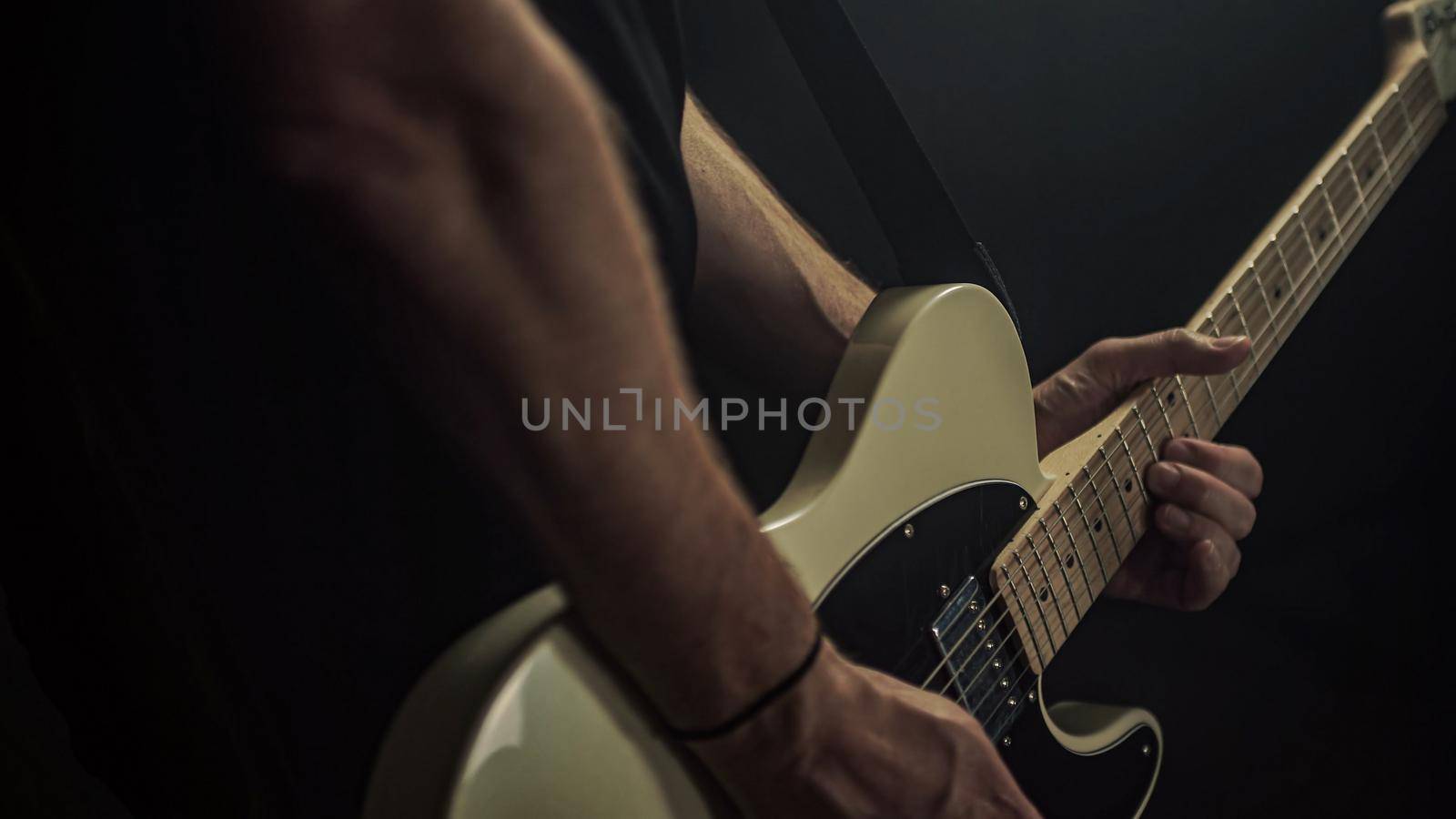A guitarist plays an acoustic guitar with details of his hand by pippocarlot