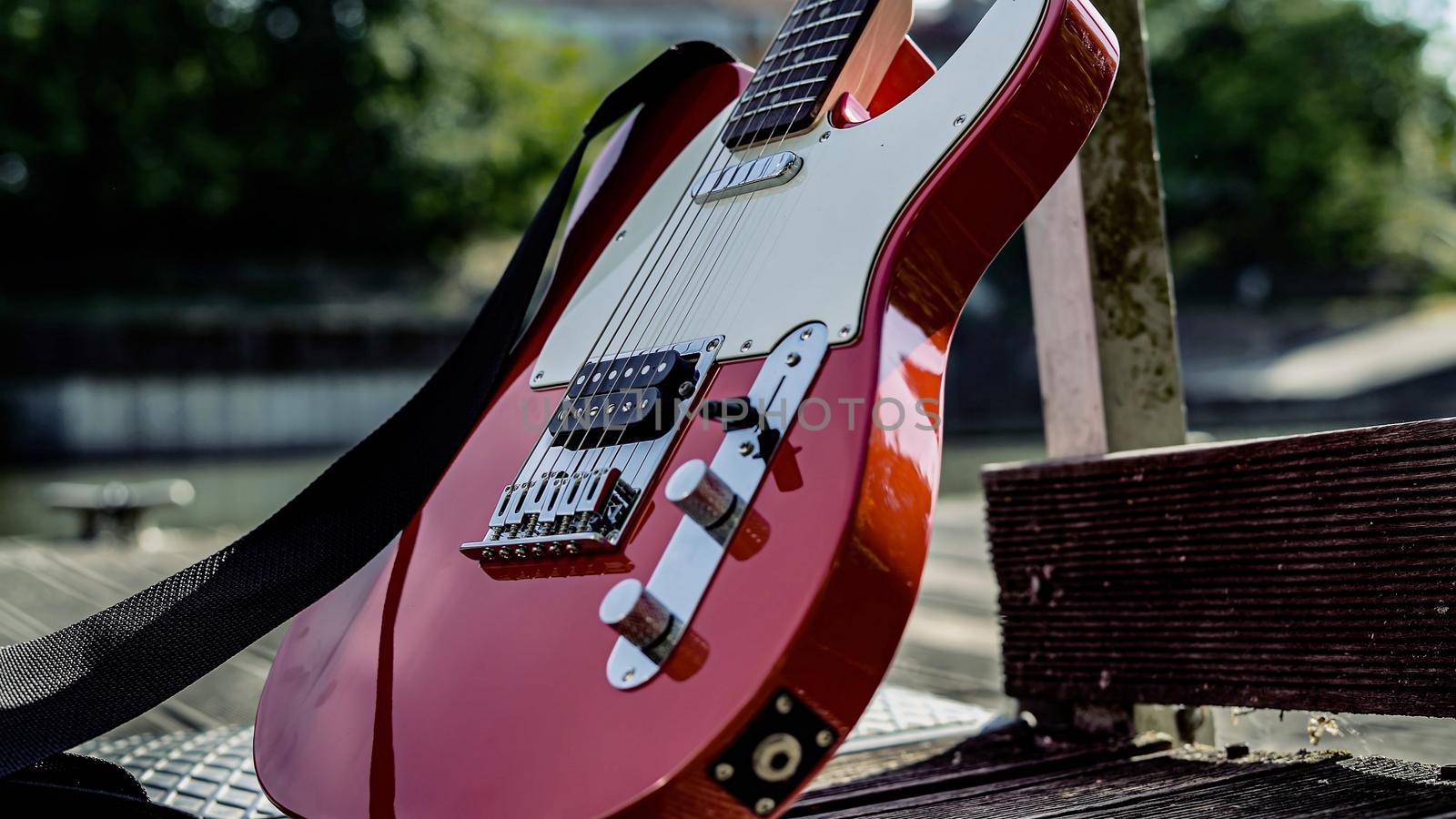 Acoustic guitar rests against wooden post on a pier with a natural background