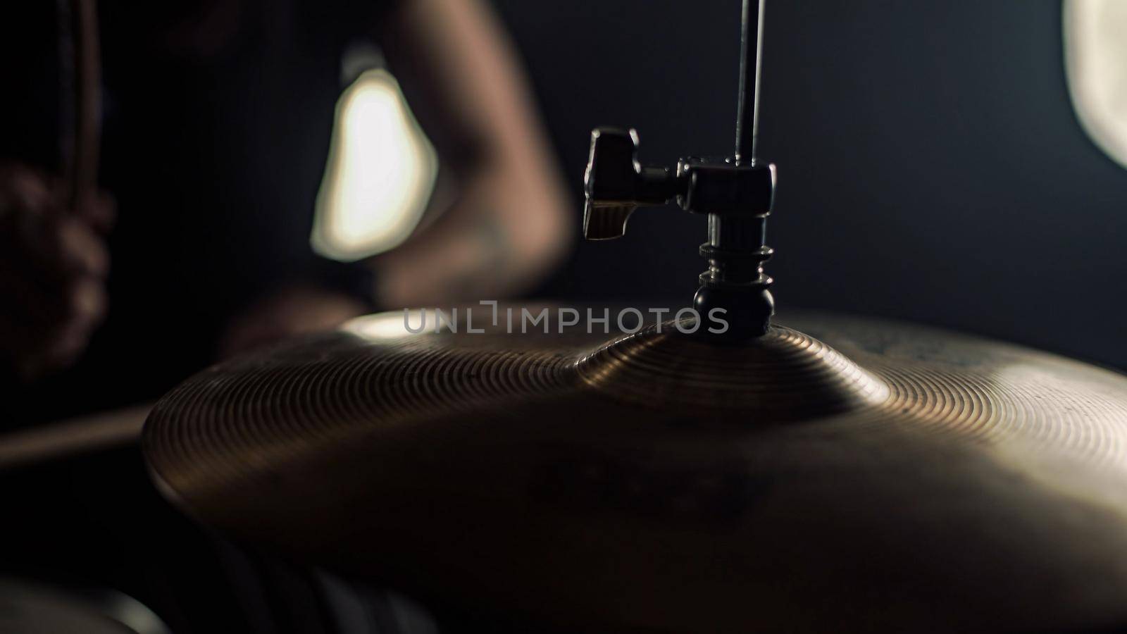 Tattooed hands of a female drummer play drum holding drumsticks