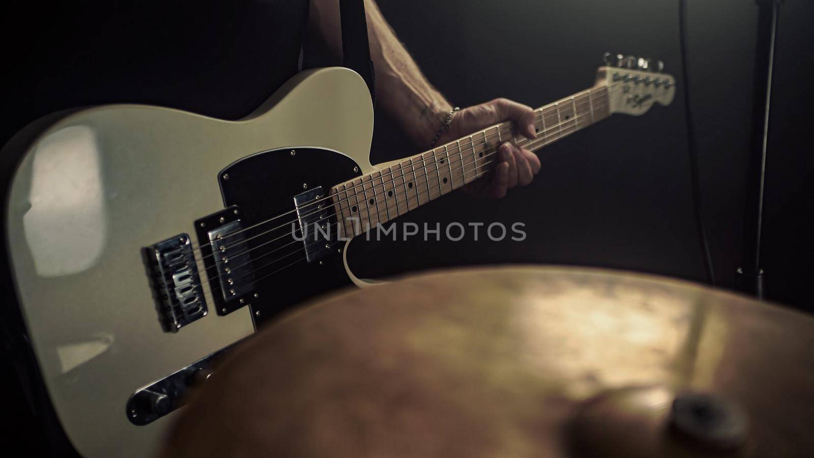 A guitarist plays an acoustic guitar with details of his hand and guitar strings