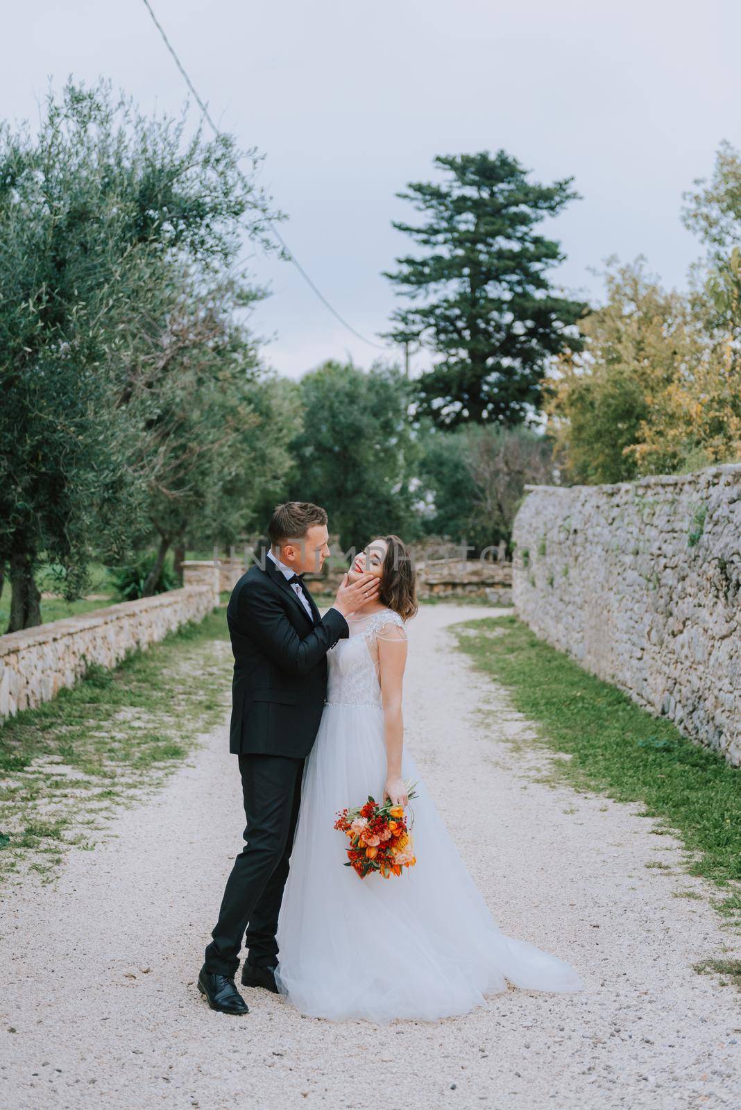 Happy stylish smiling couple walking in Tuscany, Italy on their wedding day. The bride and groom walk down the street by the hands. A stylish young couple walks. Husband and wife communicate nicely. Lovers run through the streets of the city.