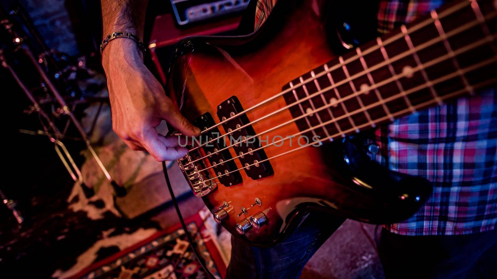 A male bass player plays a bass during a live performance on the stage