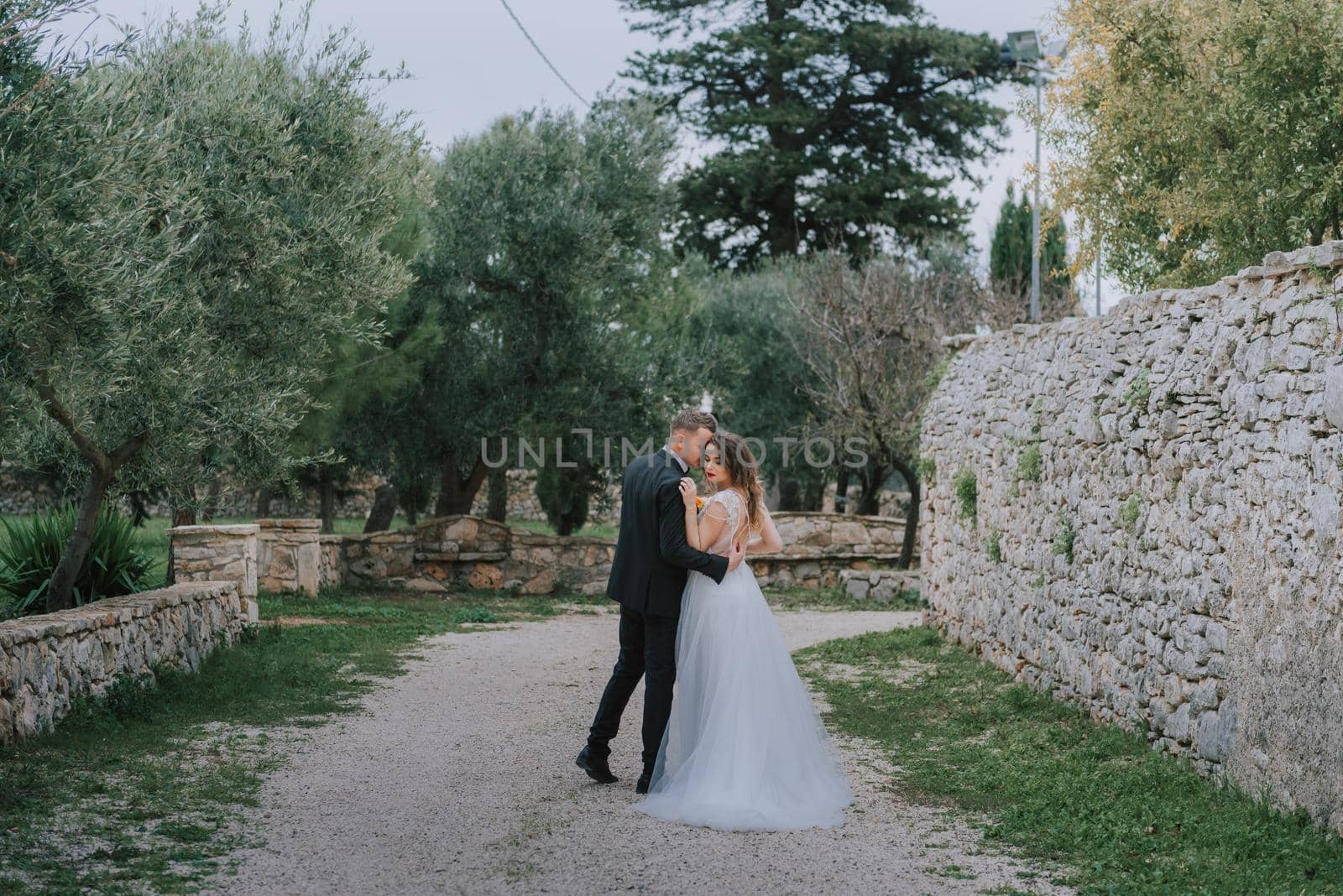 Happy stylish smiling couple walking in Tuscany, Italy on their wedding day. The bride and groom walk down the street by the hands. A stylish young couple walks. Husband and wife communicate nicely. Lovers run through the streets of the city by Andrii_Ko