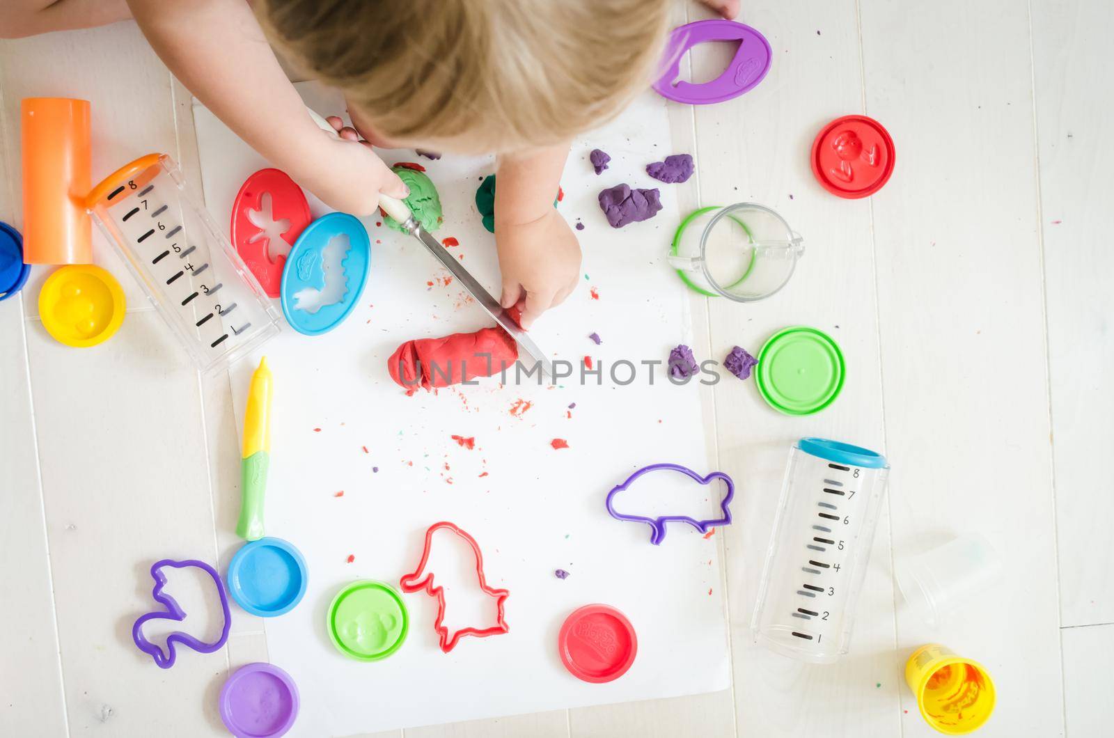 kid is playing with colourful plasticine in kindergarten by maramorosz