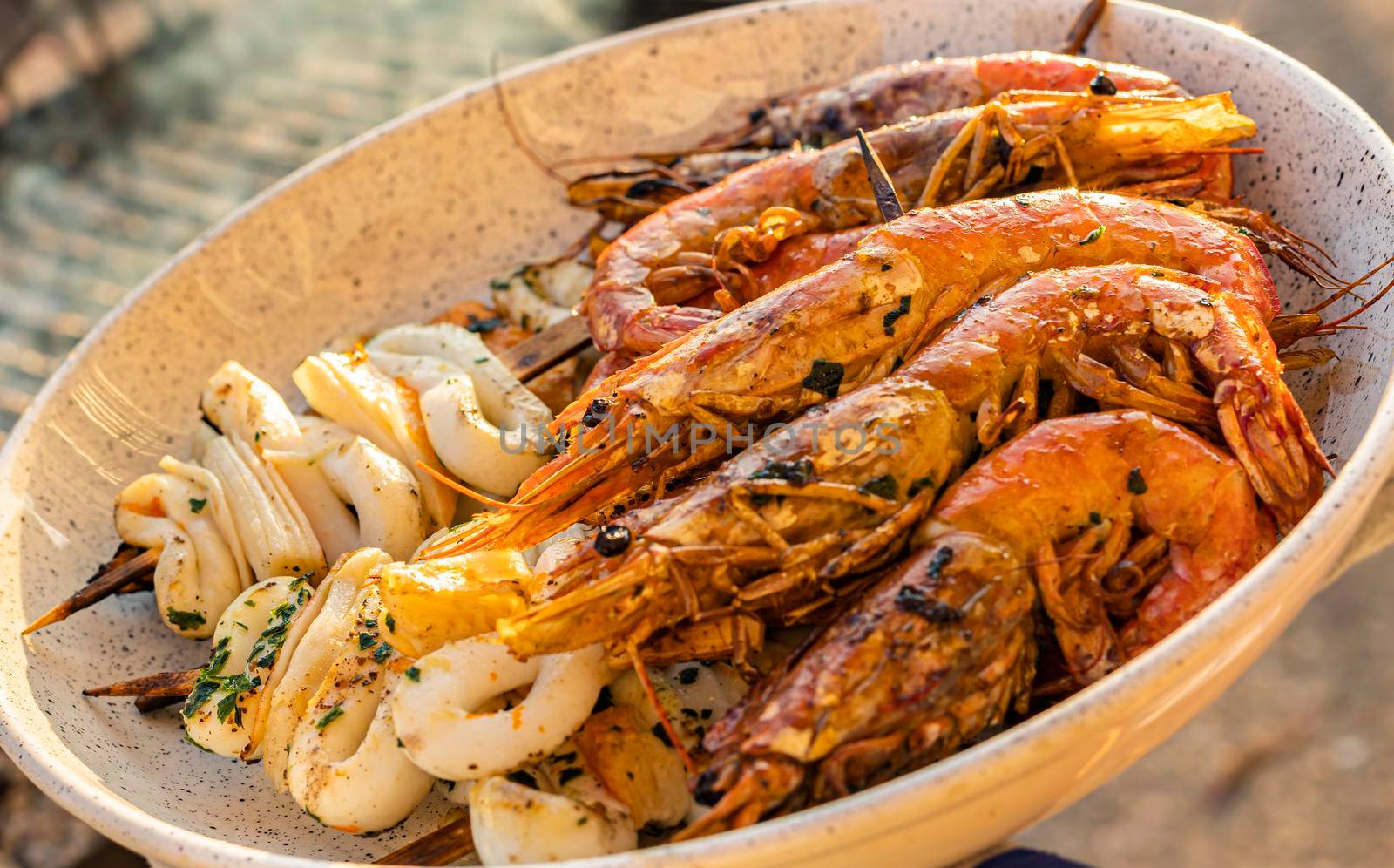 Plate of shrimp and grilled fish close up shot