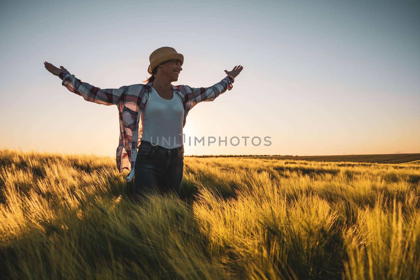 Adult woman is cultivating barley on her land. She is satisfied because of good progress of crops.