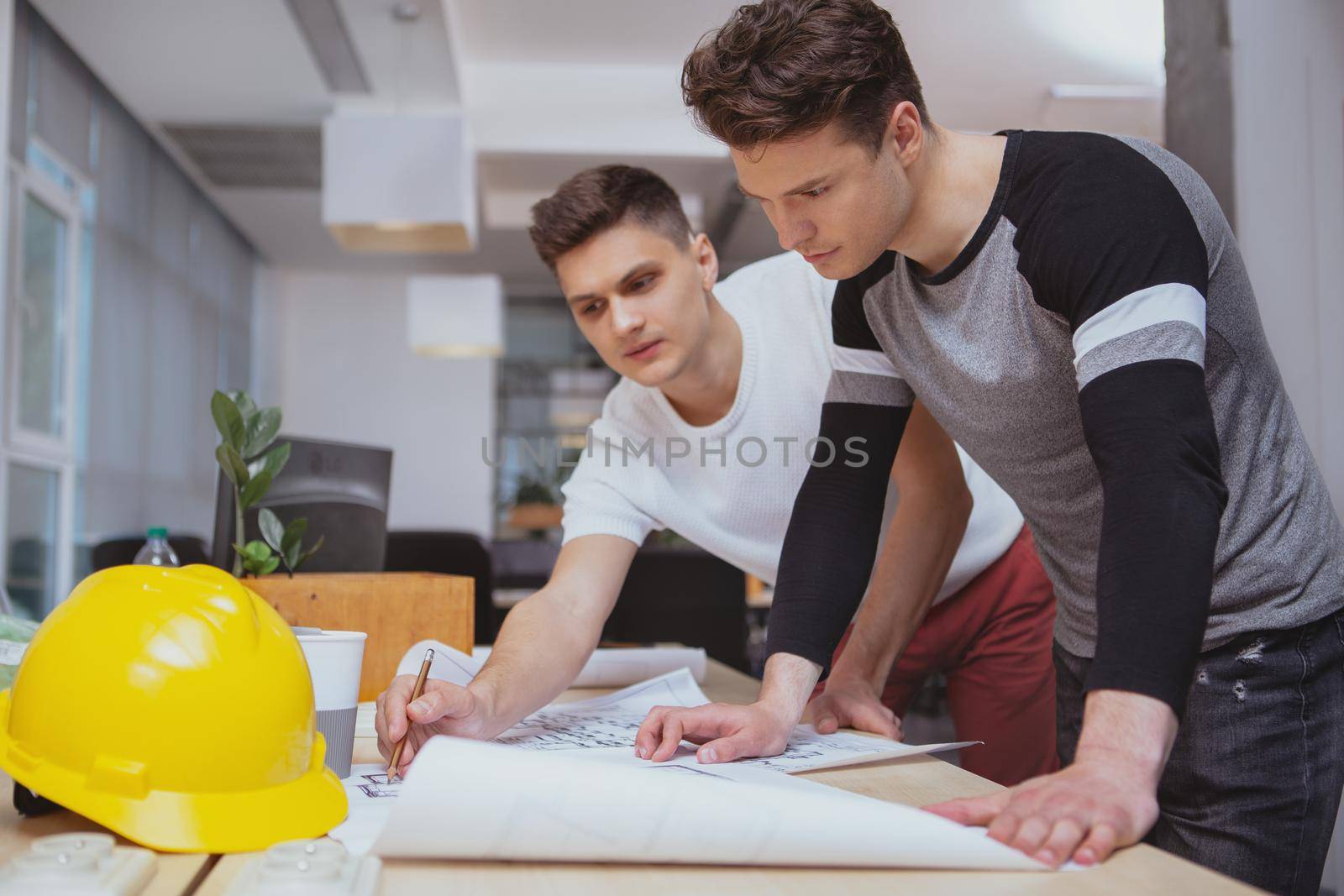 Architects at work, engineering concept. Two young male architects discussing building blueprints at the office, copy space