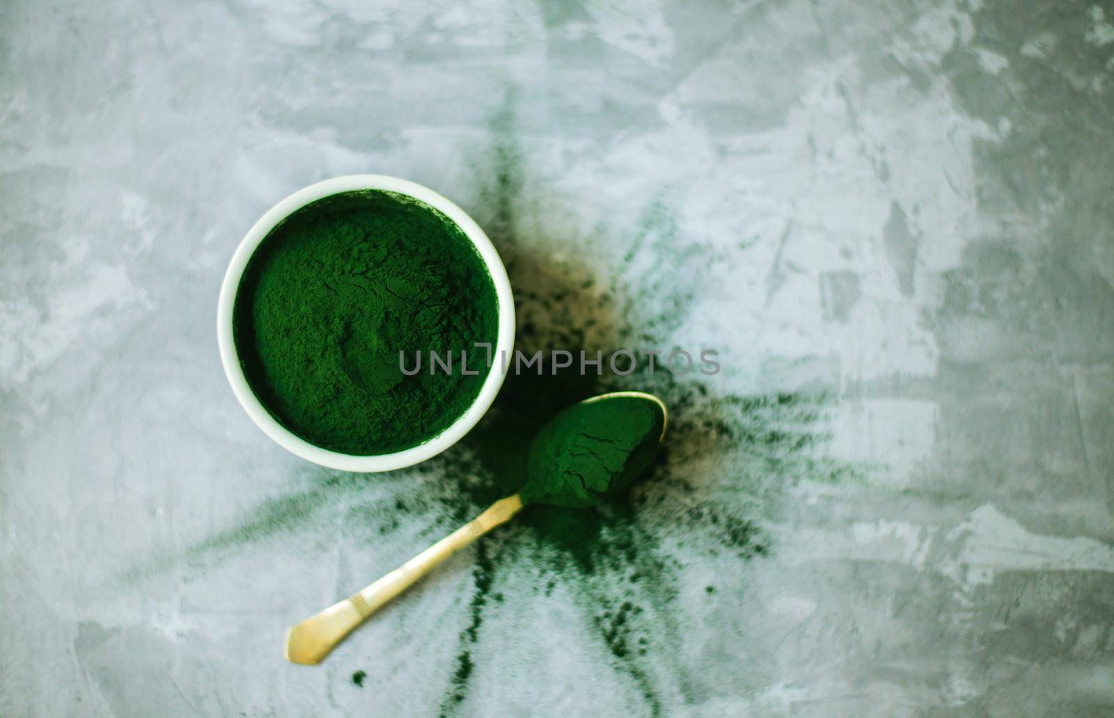 spirulina powder in white plate on concrete background by maramorosz