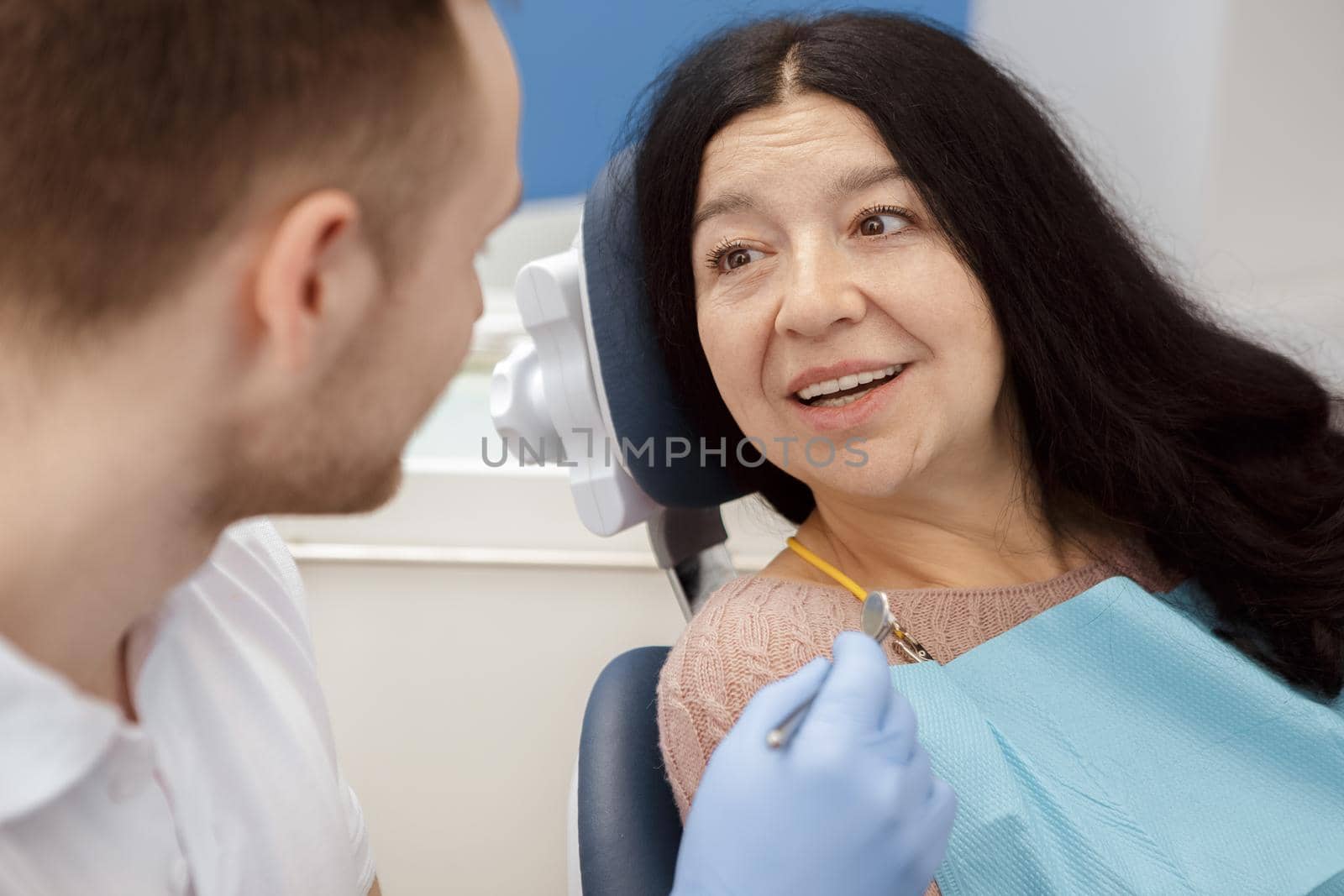Getting his advice. Senior female patient talking to her dentist at the dental clinic checkup examination healthcare helpful help questions consultation medicine professionalism support client concept