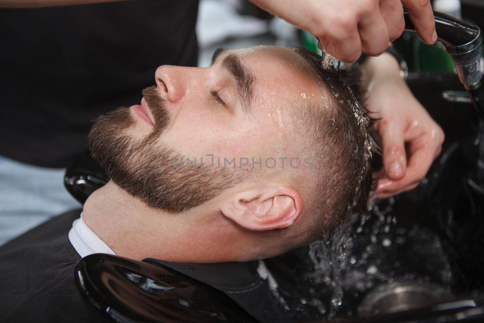 Man having his hair washed at barbershop by MAD_Production